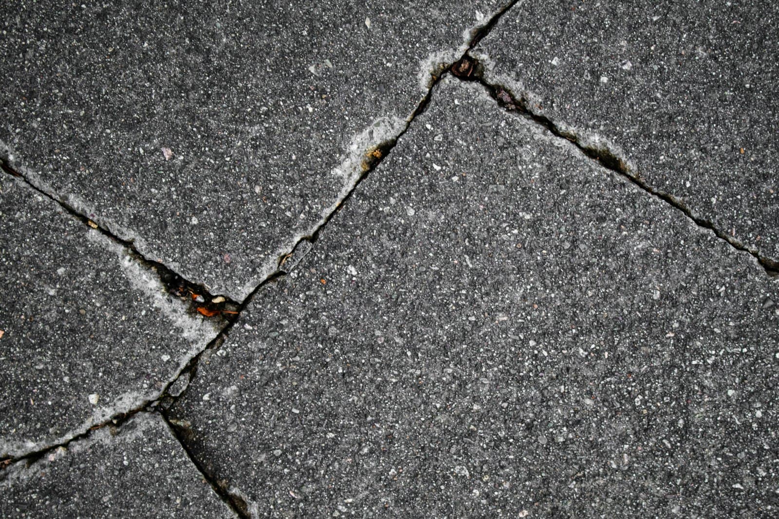 Close-up of cracked concrete pavement showing fractures and wear.